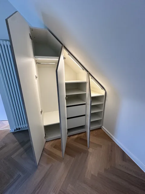 Schrank unter der Dachschräge mit beleuchteten Fächern und Schubladen