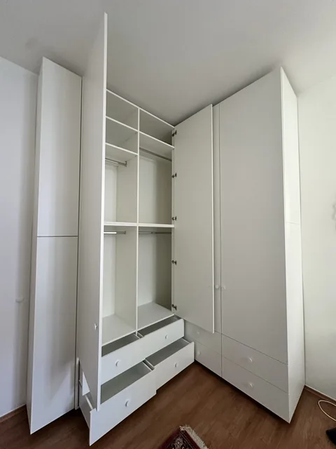 Kleiderschrank über Eck mit geöffneten Türen und Schubladen