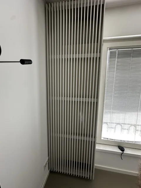 Weiße Lamellenverkleidung neben einem Fenster