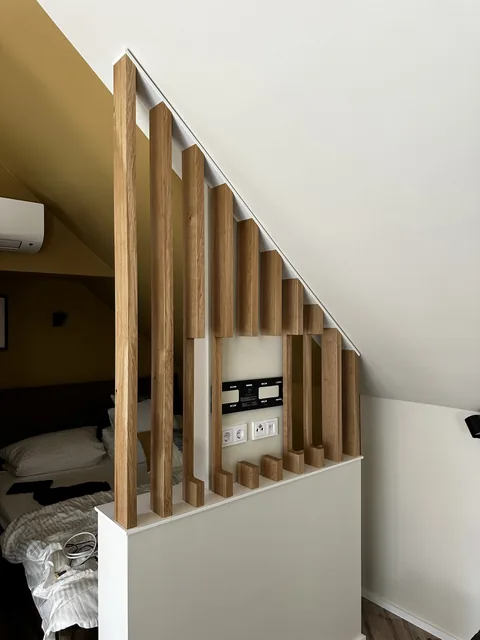 Raumteiler aus Holzlamellen unter einer Dachschräge