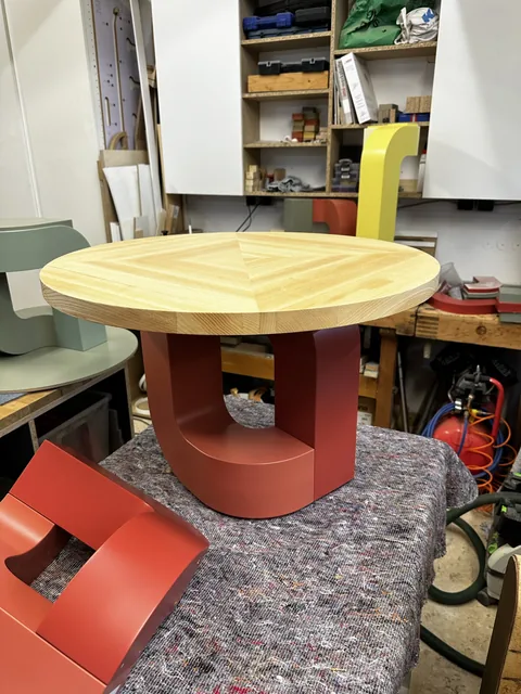 Runder Tisch mit Holzplatte und rotem Gestell