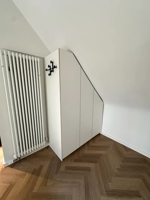 Geschlossener weißer Schrank unter der Dachschräge
