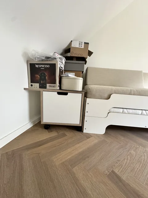 Geschlossenes Möbel auf Rollen neben dem Bett