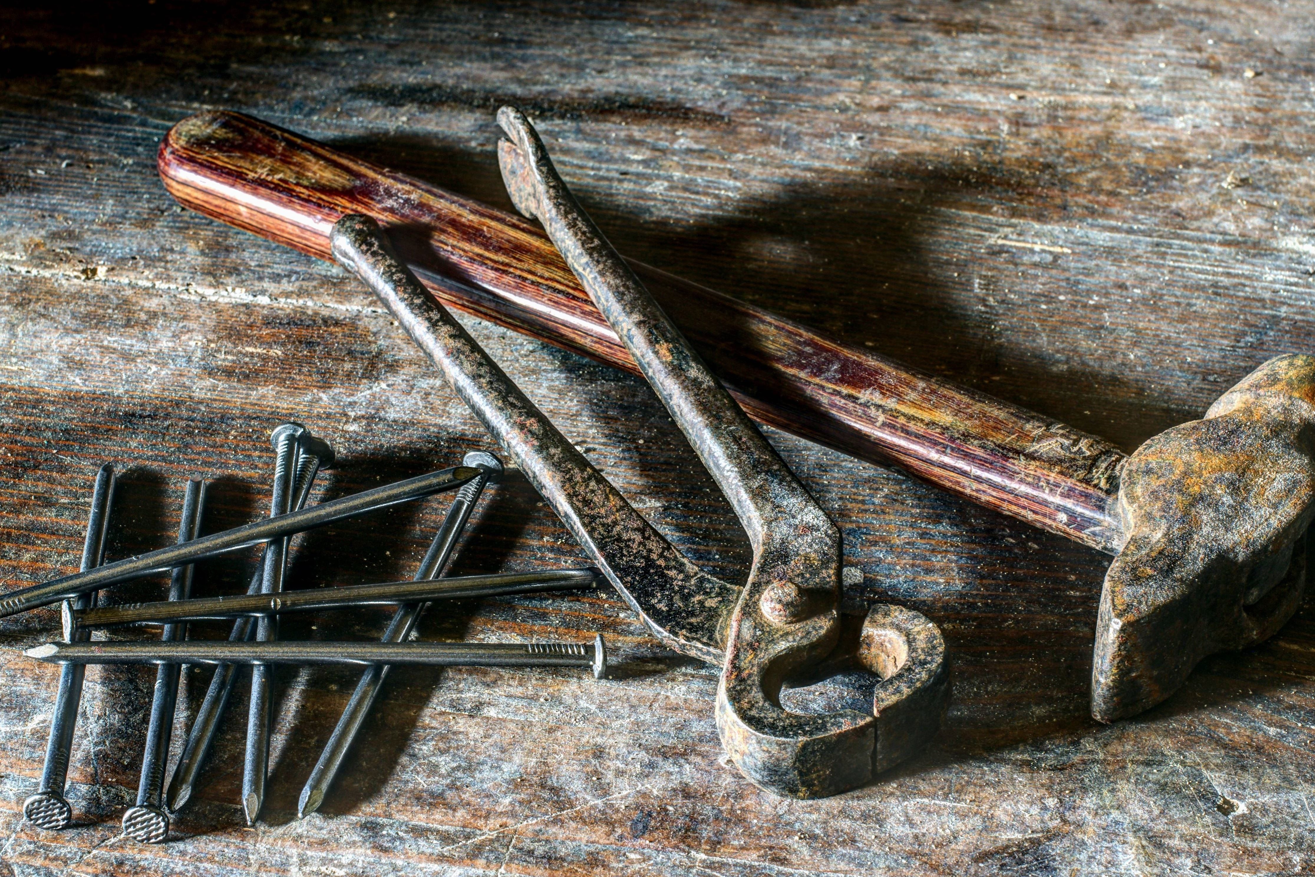 Altes Handwerkzeug auf einer Holzwerkbank: Hammer, Zange und Nägel